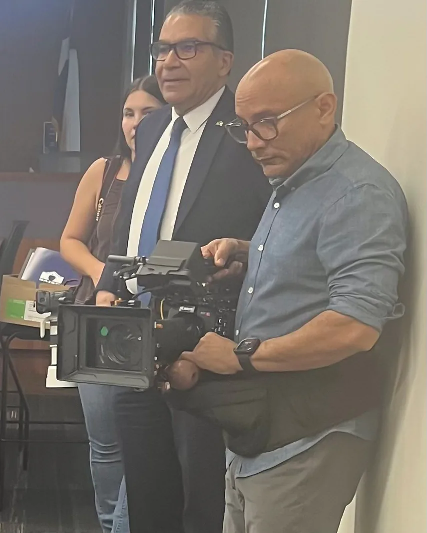 Carlos Javier Sanchez, cámara en mano, graba junto al exsuperintendente del SAISD, Jaime Aquino, en una ceremonia de graduación.