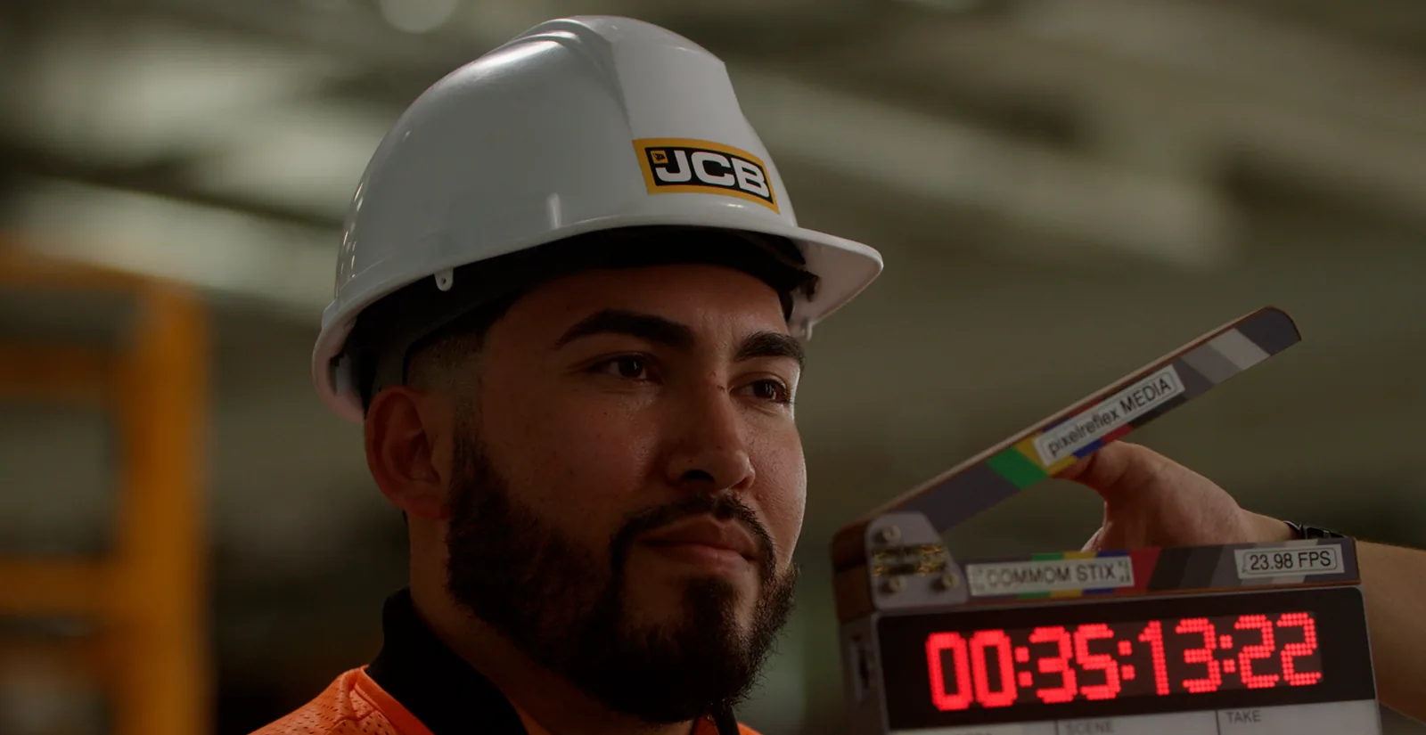 Jose Gonzalez, aprendiz de mantenimiento de JCB, con el casco de la empresa puesto, espera a que den claqueta para empezar su entrevista.