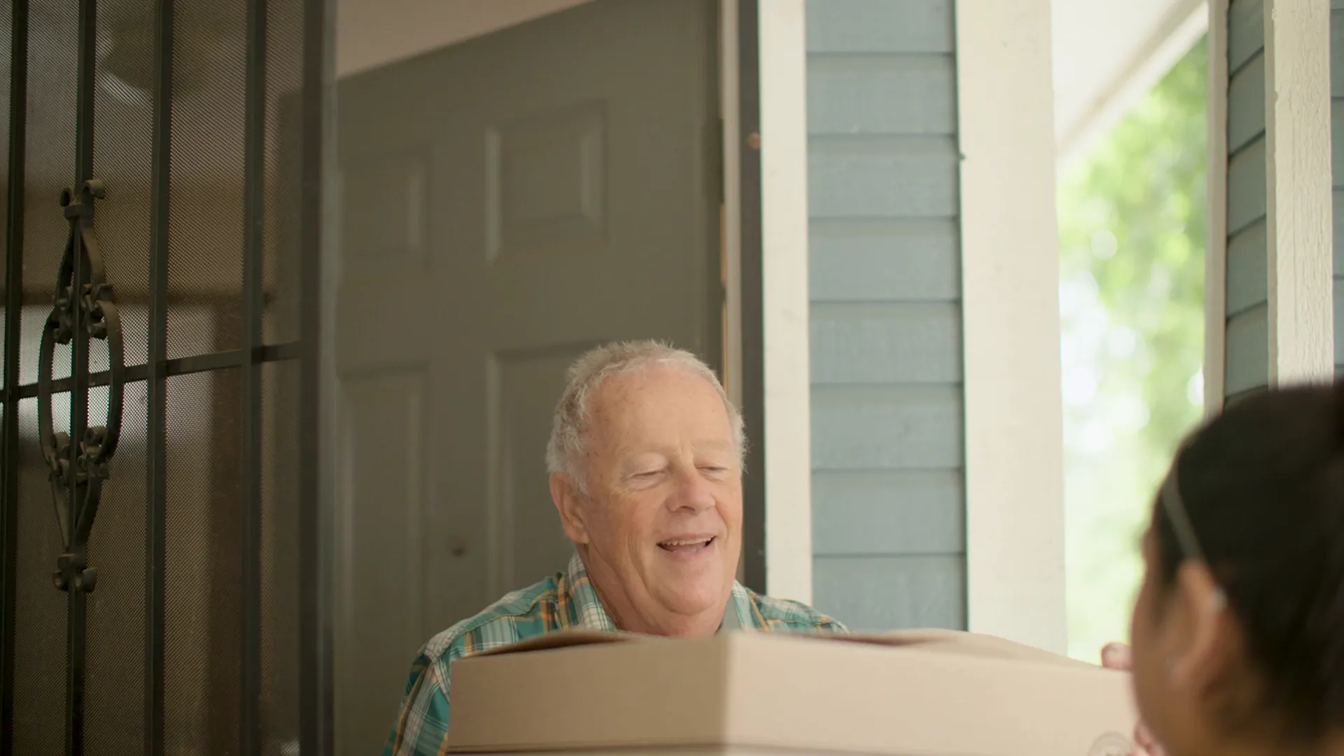 A smiling man carries a box through a front door, from our LISC San Antonio video.