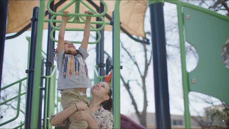 Ashley Keen helps a child swing from playground monkey bars in her SAMMinistries story.