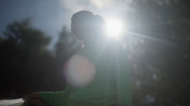 Sunlight breaks through the trees behind a person in silhouette, from our Bexar Branches Alliance video.