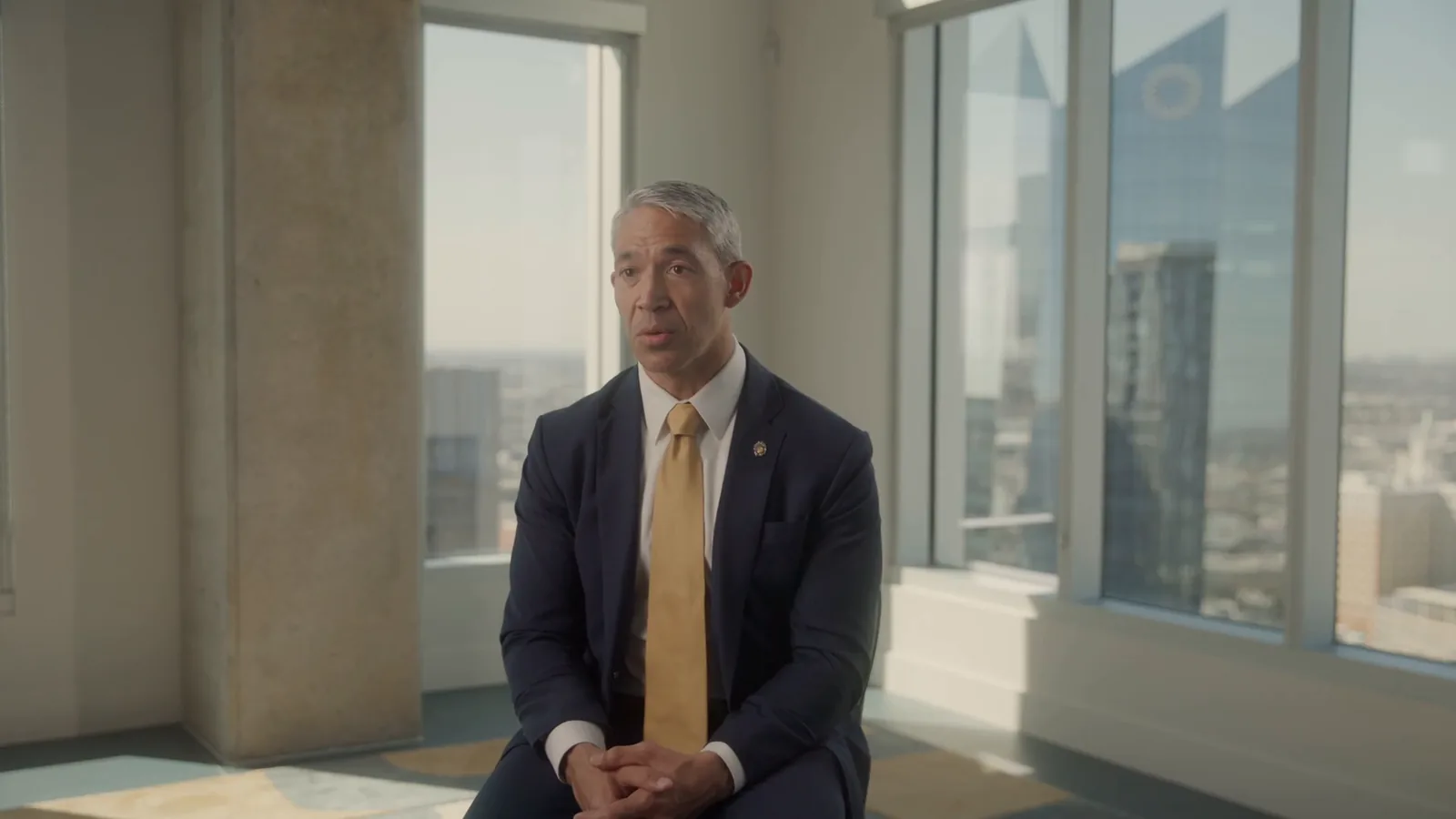 Former San Antonio Mayor Ron Nirenberg is interviewed by tall windows overlooking downtown.