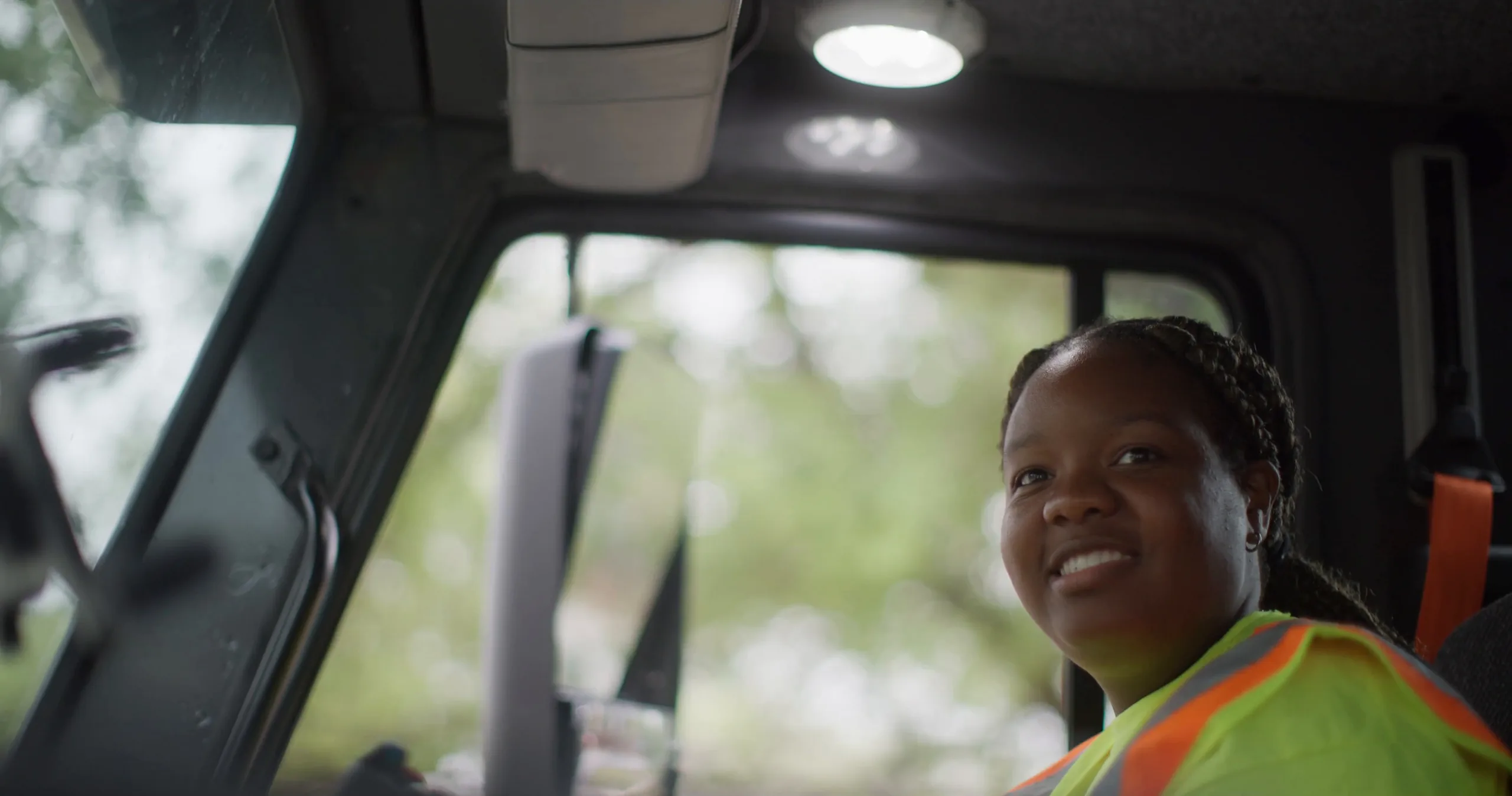 Tayler Lang, a side loader operator, smiles from her truck cab in our City of San Antonio Workforce Development video.