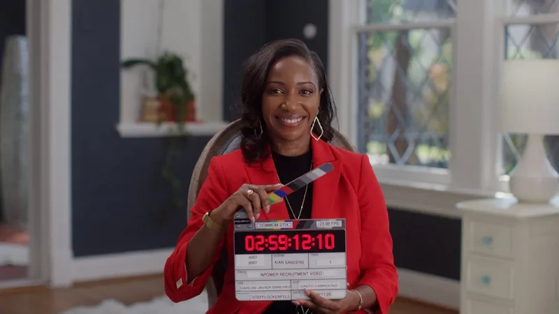Kian Sanders, in a red blazer, smiles as she holds the slate before her NPower interview.