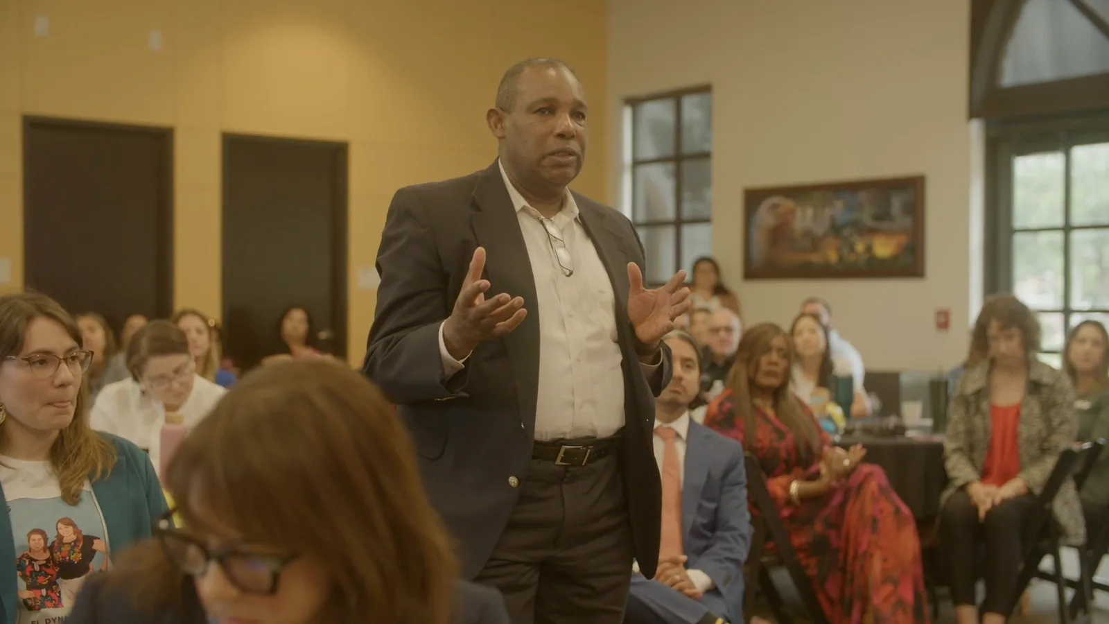 A man stands and speaks to a packed room at the National Apprenticeship Day event in San Antonio.