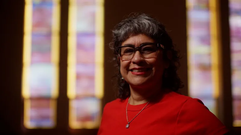Roxy Caldbeck smiles in front of stained glass windows in her SAMMinistries Journeys of Hope story.