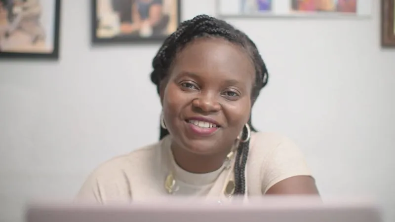 NPower alum Patience Gyakari smiles at her laptop in a home office.