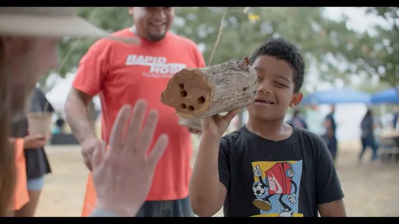 A boy holds up a log and gets a high five at Día del Árbol, the City of San Antonio Arbor Day celebration.