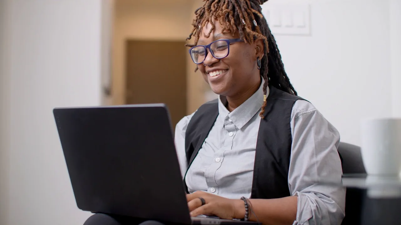 NPower alum Brittany Holmes smiles as she works on her laptop.