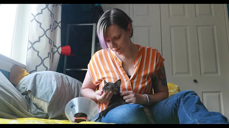 Maria Rusert, San Antonio Pets Alive! Cat Foster of the Year, holds a small black cat on her bed.