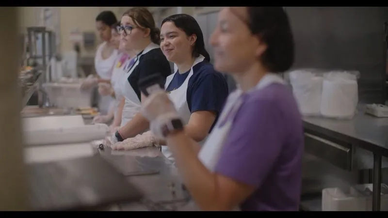 Students of Service volunteers in aprons serve food in the Haven for Hope kitchen.