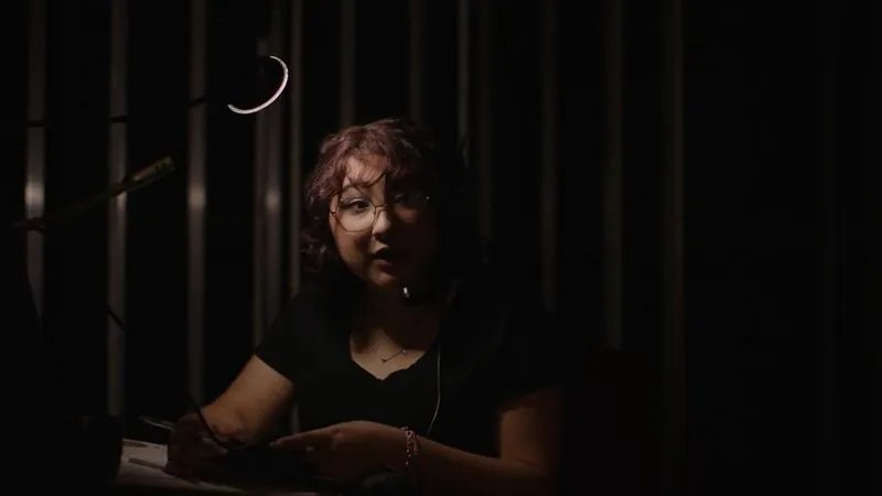 An Edgewood Fine Arts Academy student in glasses sits in a dark theater for her spotlight profile.