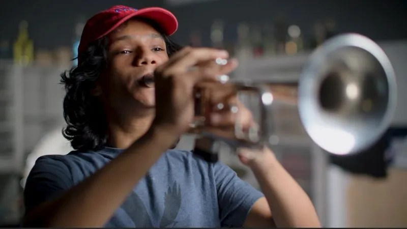 A Memorial High School musician in a red cap plays the trumpet.