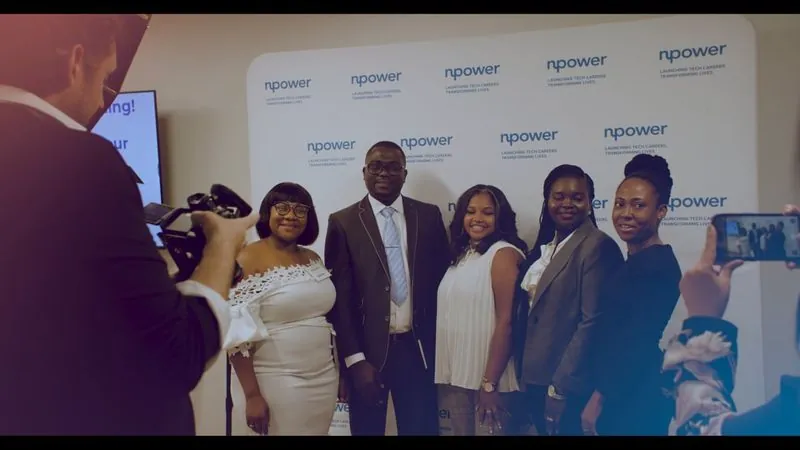 NPower San Antonio graduates pose in front of an NPower backdrop as a camera operator films.
