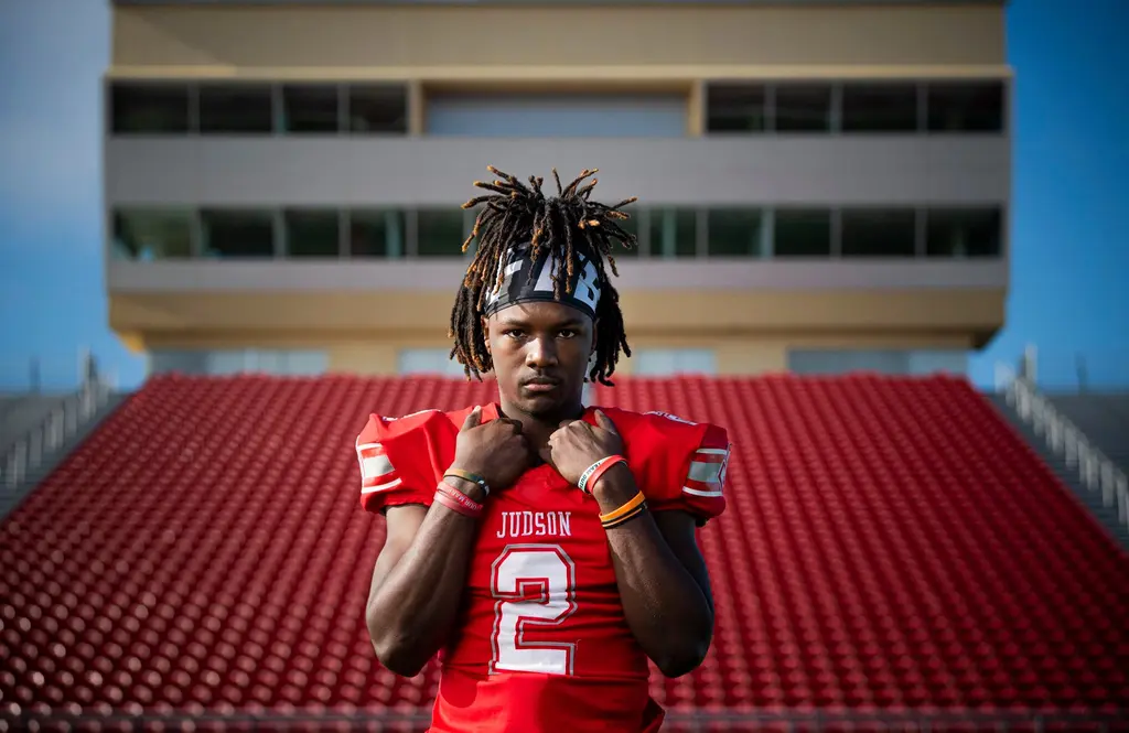 Judson football player in a red No. 2 jersey standing in front of empty red stadium seats