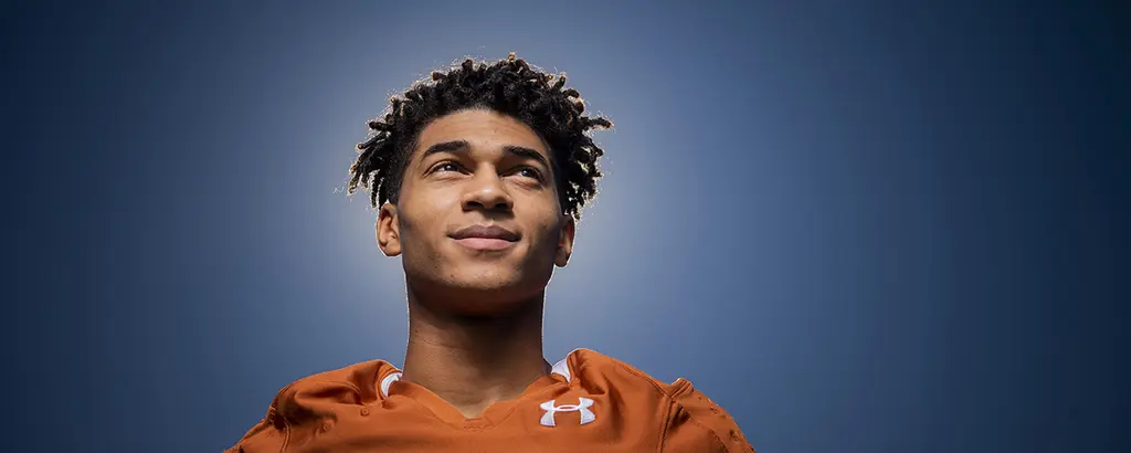 Dante Heaggans in an orange shirt gazing upward against a glowing blue backdrop