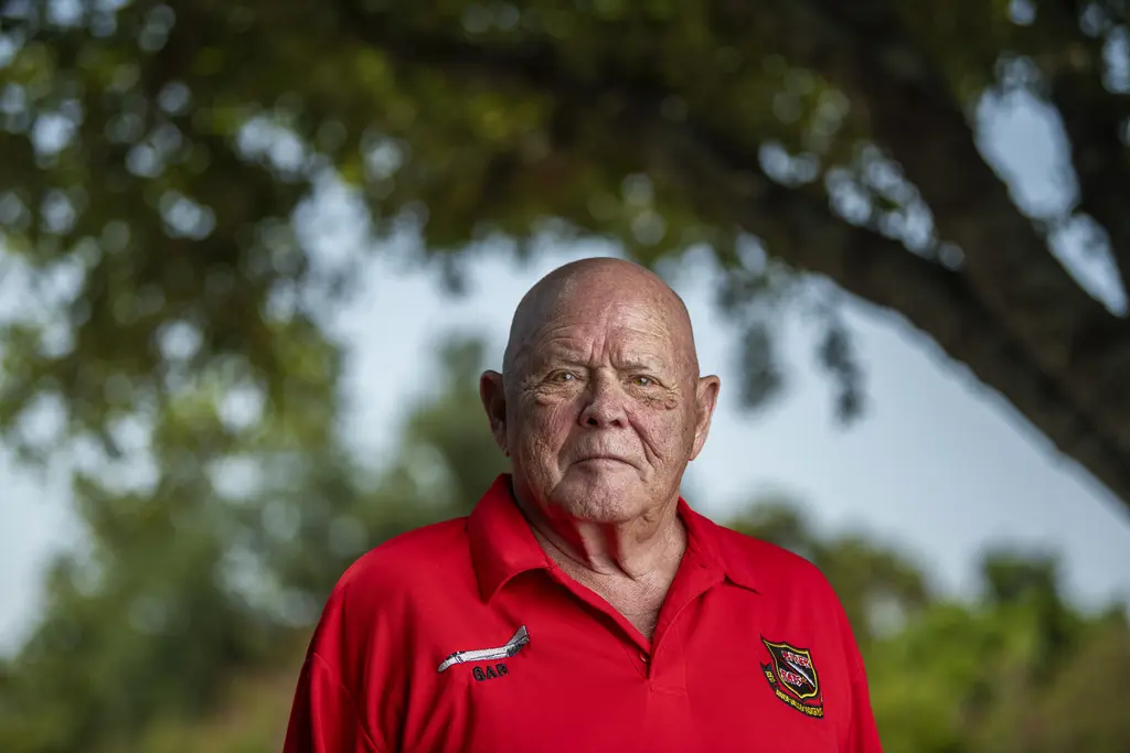 George Alan Rose, a retired Air Force officer, in a red polo shirt beneath a shade tree