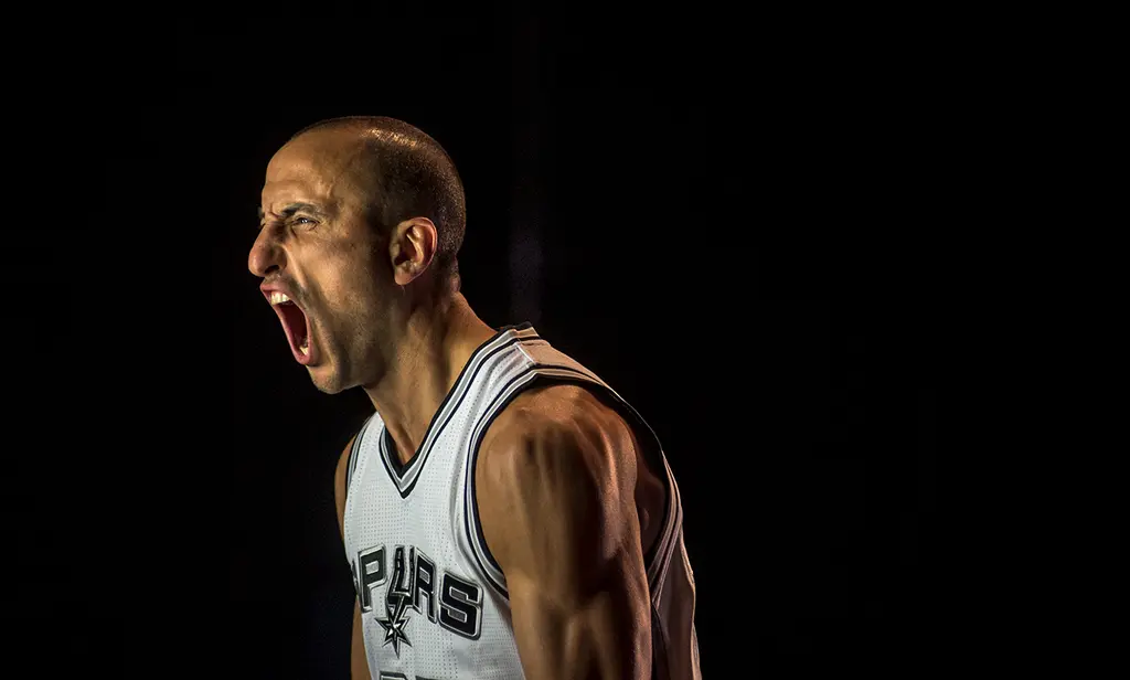 Manu Ginobili in a white Spurs jersey screams in profile against a black background