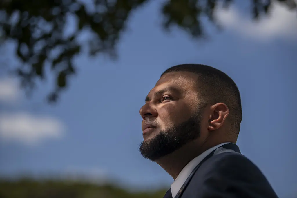 Charles Henry in a suit, shown in profile against a blue sky and tree branches