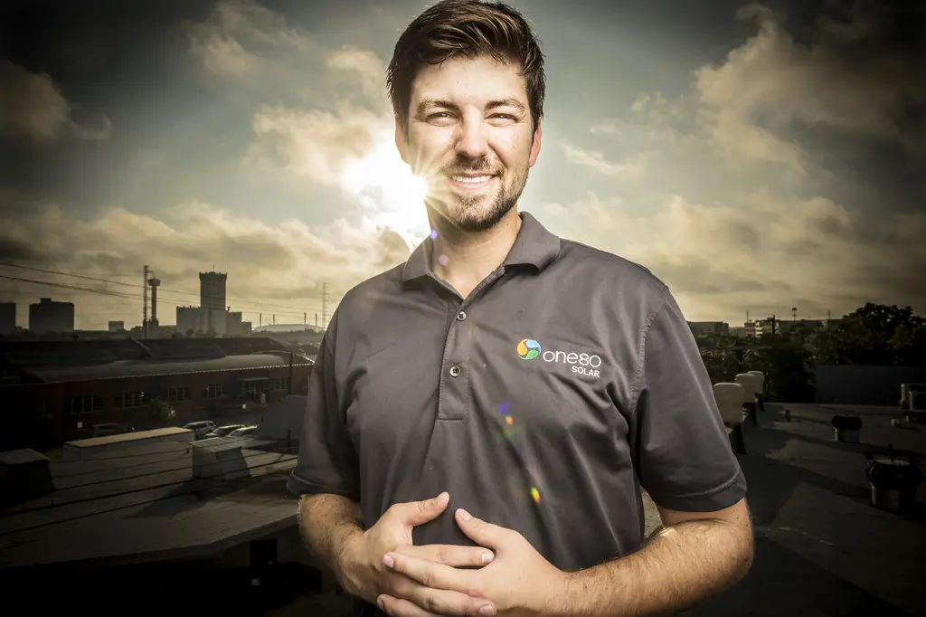 Patrick Attwater in a One80 Solar polo smiling on a rooftop as the sun breaks through clouds