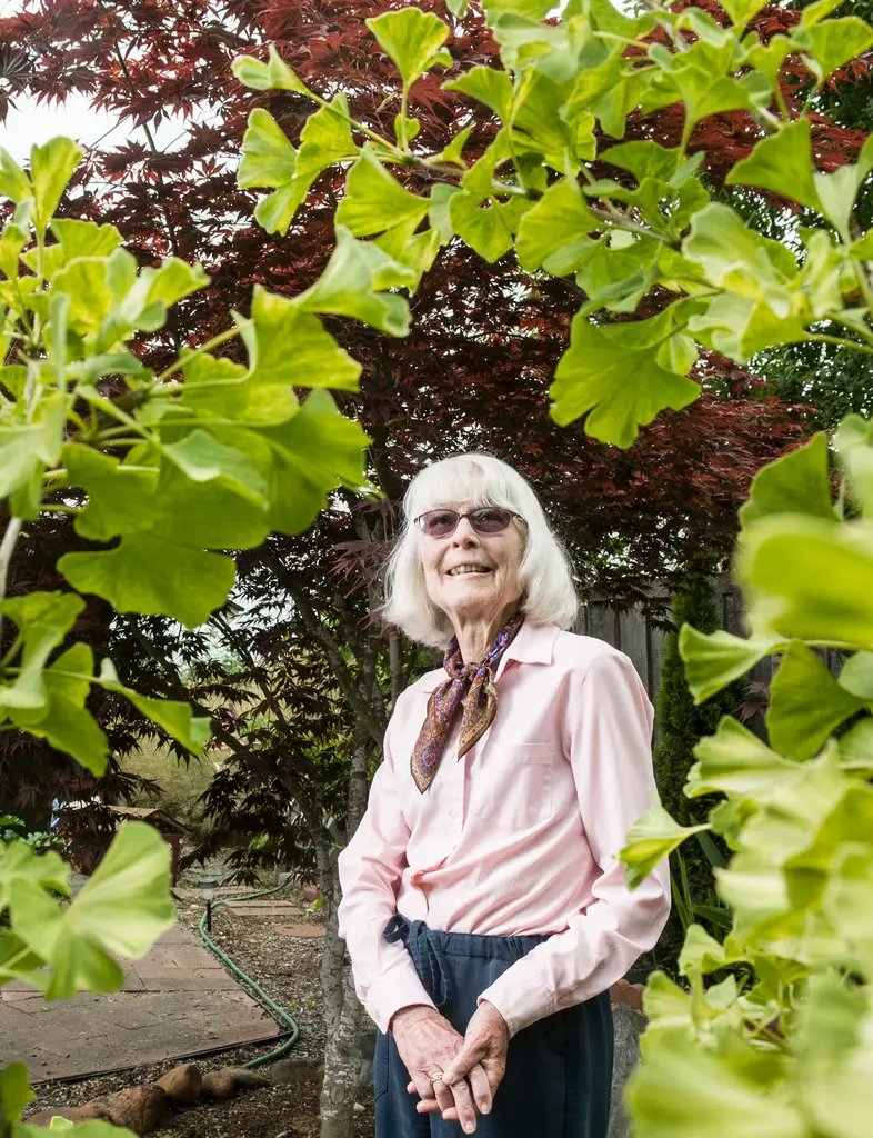 Bernice Youtz in a pink blouse and silk scarf stands framed by bright green ginkgo leaves
