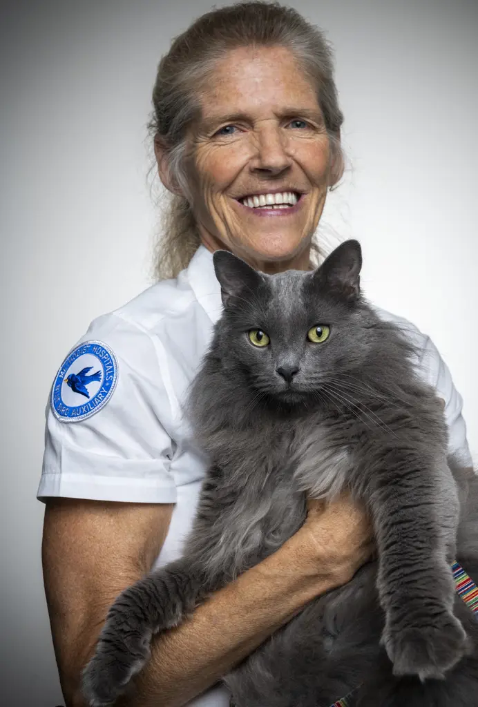 Beverly Oakes smiles as she holds her gray long-haired cat, Zane Grey.