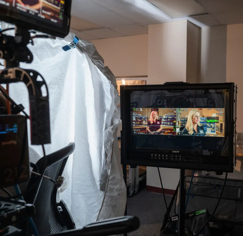 Un monitor muestra a Deborah Carter, de Bexar County, desde dos ángulos de cámara durante su entrevista para el video TX Fast Track Program, junto a una cámara de cine y un difusor blanco.