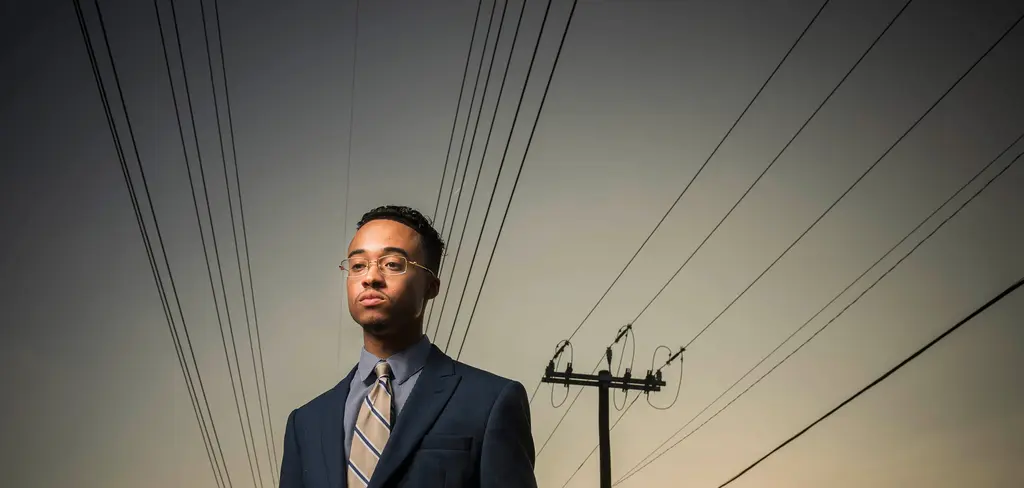 Dieter Cantu in a suit and tie stands beneath power lines against a pale sky