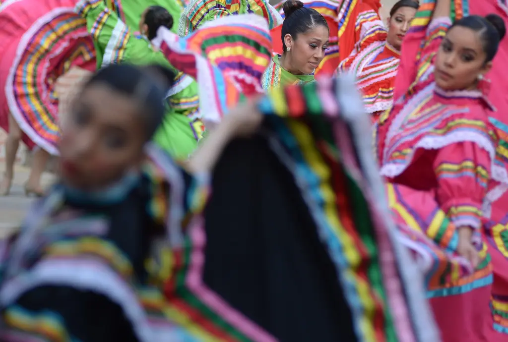 Folklorico dancers in bright ruffled dresses swirling their skirts during a performance