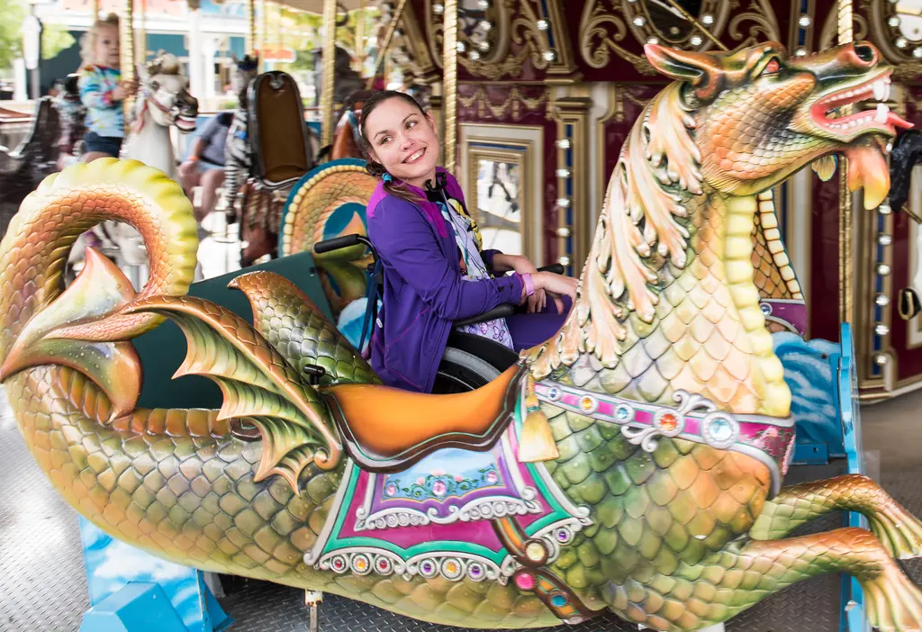 Morgan Hamill smiles as she rides a sea dragon chariot on the carousel at Morgan's Wonderland