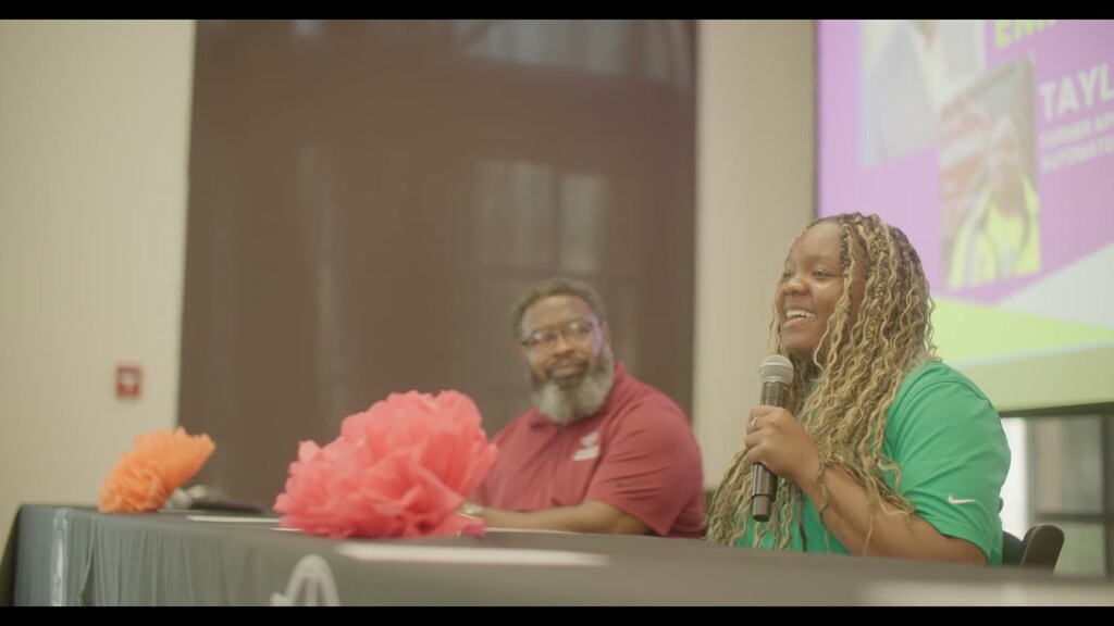 Two panelists smile at a table during the National Apprenticeship Day event in San Antonio, one holding a microphone.