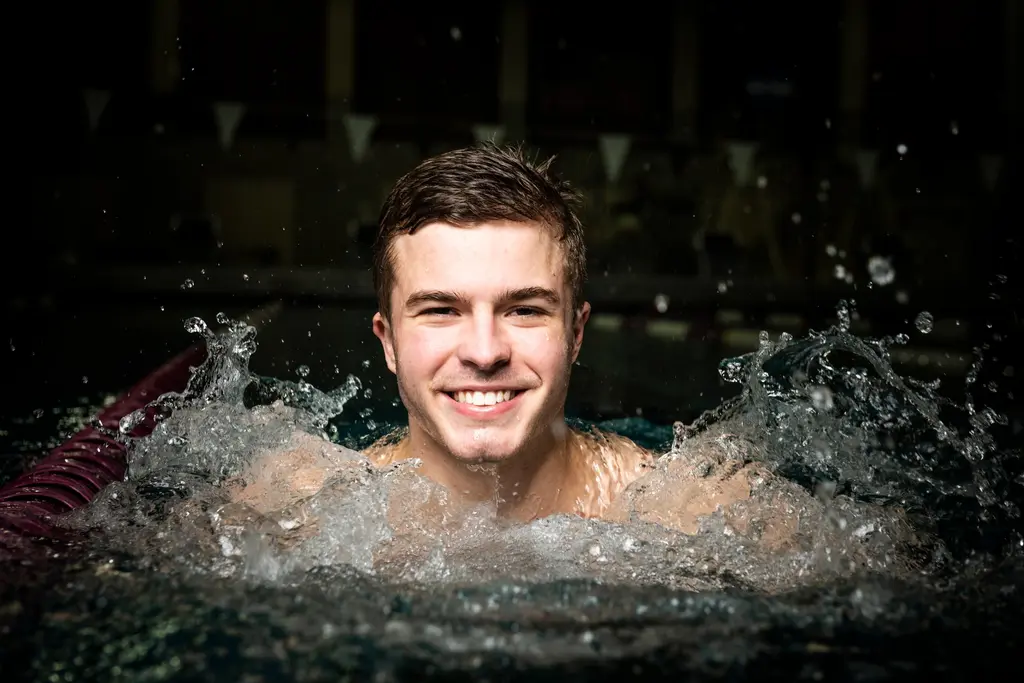 Harlan High School diver Nicholas McCann grins as water splashes up around him in the pool.