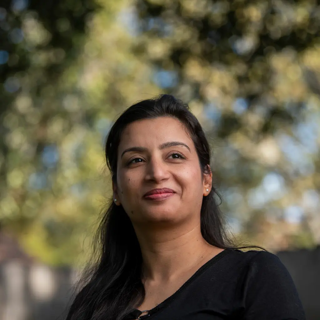 Anju Kumari looks up in soft light with trees behind her.